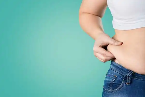 Image of woman pinching her love handles to show weight gain